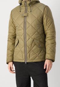 Olivgrüne gesteppte Jacke mit Kapuze, Reißverschluss und Druckknopfakzent. Verfügt über Vorderentaschen und eine glatte, glänzende Textur.