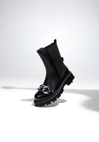Bottines noires avec une tige en cuir lisse, semelle en caoutchouc épaisse et accent en chaîne argentée sur l'orteil. Équipées d'une sangle de tirage pour un enfilage facile.