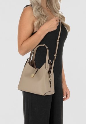 Sac à main en cuir beige avec des poignées courtes et une bandoulière réglable. Équipé de quincaillerie dorée et d'un compartiment zippé.