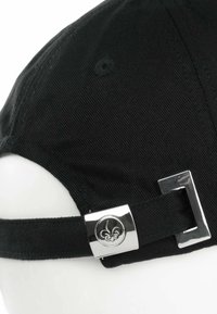Cappello nero con una texture morbida e visiera curvata. Presenta una fibbia metallica argento con un emblema di giglio sulla cinghia regolabile.