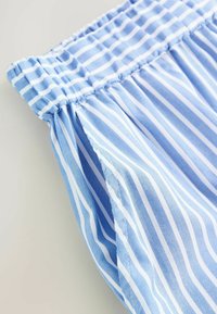 Tessuto azzurro chiaro con strisce verticali bianche. Vita elasticizzata arricciata con texture liscia. Cuciture ordinate lungo i bordi.
