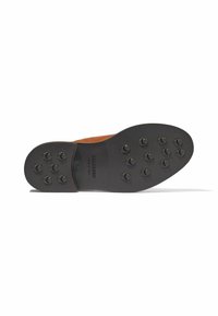 Suola di scarpa in camoscio marrone con una resistente base in gomma nera, caratterizzata da 10 chiodi di trazione circolari e un motivo superficiale testurizzato.