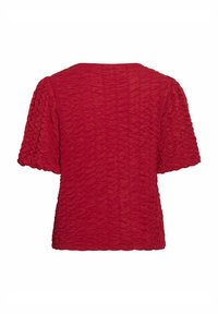 Haut texturé rouge avec des manches courtes bouffantes, un col rond et un design en tissu plissé froncé.