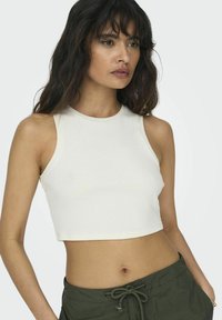 Witte geribbelde crop top met hoge hals en zonder mouwen, gecombineerd met olijfgroene shorts met trekkoord. Gladde textuur en aansluitende pasvorm.