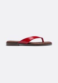 Sandale string en cuir verni rouge avec semelle intérieure coussinée marron et semelle plate noire, vue de profil sur fond blanc.