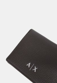Portafoglio in pelle marrone scuro con superficie testurizzata, con logo A/X in metallo argentato sul davanti. Forma rettangolare con angoli arrotondati.