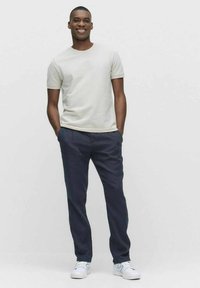 Ljusgrå t-shirt med kort ärm som kombineras med marinblå byxor och vita sneakers. Outfitten har en avslappnad passform och en mjuk textur.