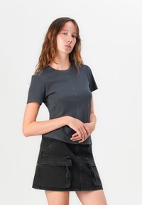 Mörkgrå passformad t-shirt med korta ärmar, med en central sömdetalj, kombinerad med en svart denimkjol med fickdetaljer.