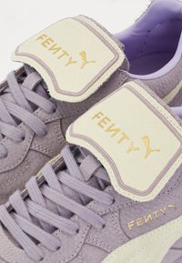 Purple Fenty x Puma sneakers with textured suede, leather accents, flat laces, gold branding on tongue, and a smooth inner lining.