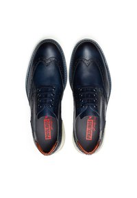 Chaussures en cuir bleu marine avec des brogues, à bout rond et à lacets. Accentuées par un talon marron et une semelle blanche. Fini texturé.