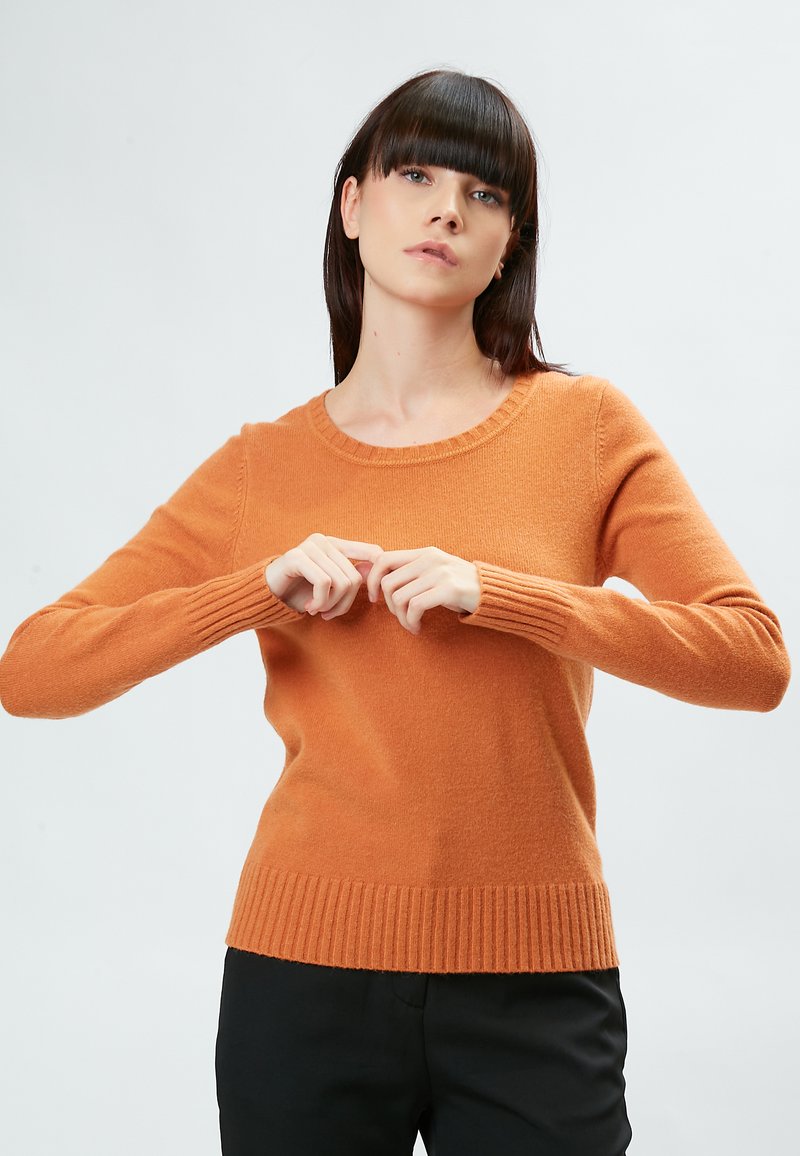 Suéter de color óxido con cuello redondo, mangas largas y puños y dobladillo acanalados. Fabricado en un tejido suave y texturizado.