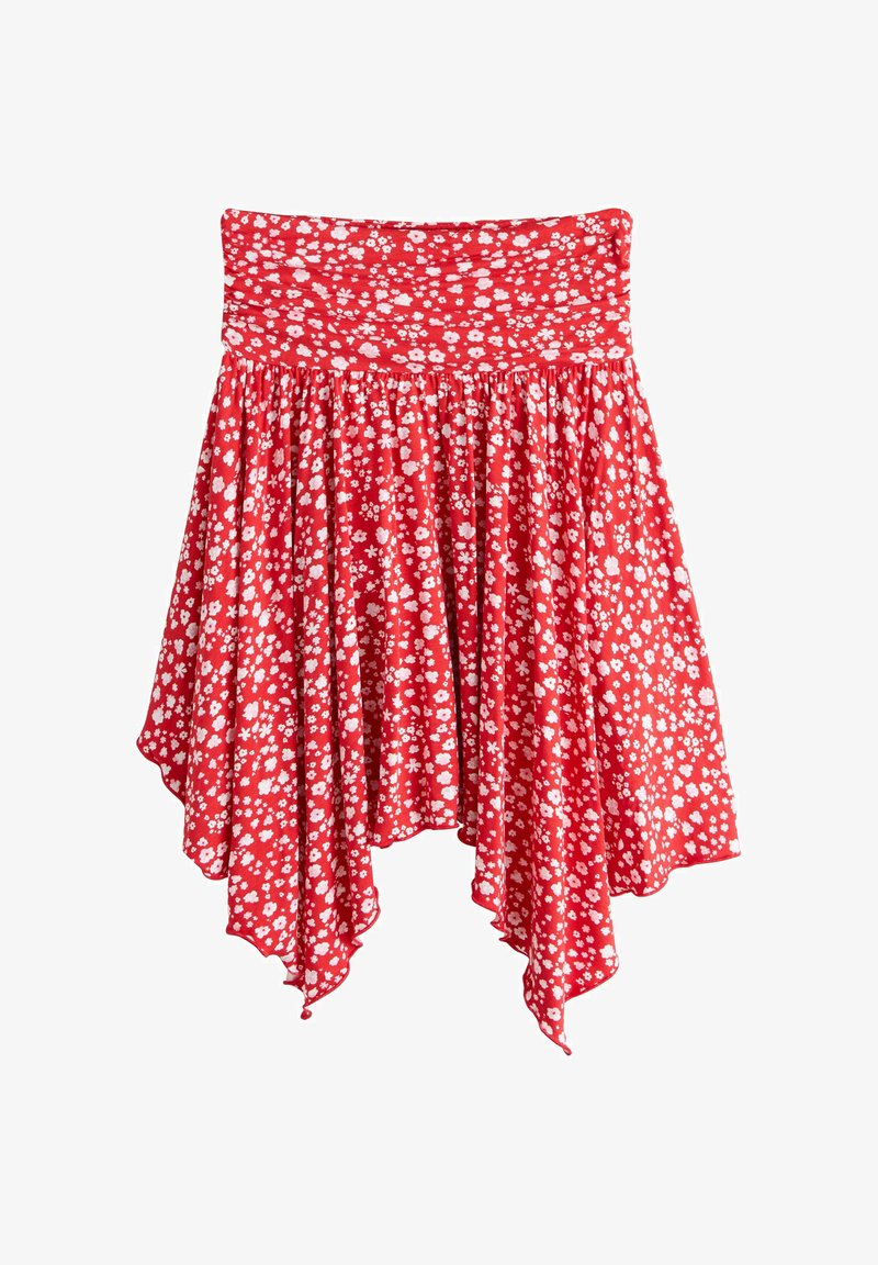 Jupe rouge avec petit motif floral blanc, taille élastique et ourlet asymétrique en forme de mouchoir.