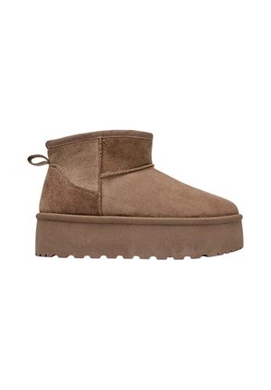 Bottine en daim marron avec une semelle épaisse et une pointe arrondie. Elle comporte une couture sur le côté et une languette à l'arrière pour un enfilage facile.