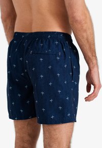 Marine zwemshorts met een palmbomenpatroon, elastische tailleband en een achterzak. De stof heeft een structuur uitstraling.