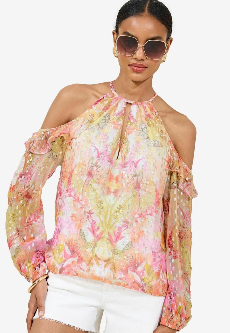 Blusa trasparente con spalle scoperte e maniche a volant, con un motivo floreale in tonalità pastello di rosa e giallo, accentuata da dettagli metallici.