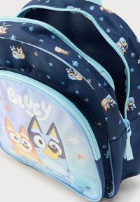 Σακίδιο πλάτης σε ναυτικό μπλε χρώμα με κινούμενα σχέδια, μπλε λεπτομέρειες και σχέδια με αστέρια. Διαθέτει μεγάλο μπροστινό τσέπη με τυπωμένο σχέδιο και φερμουάρ κλεισίματα.