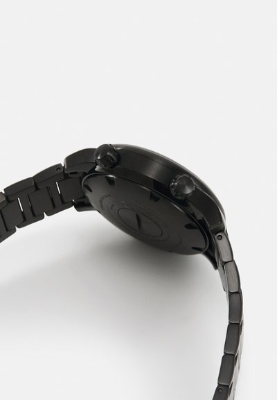 Black metal wristwatch with a smooth round case, two push buttons, a textured band, and a minimalist design on the back.