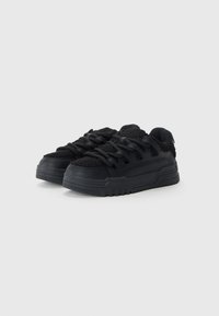 Black sneakers featuring a textured upper with soft, wool-like material, thick rubber sole, and prominent laces for secure fit.