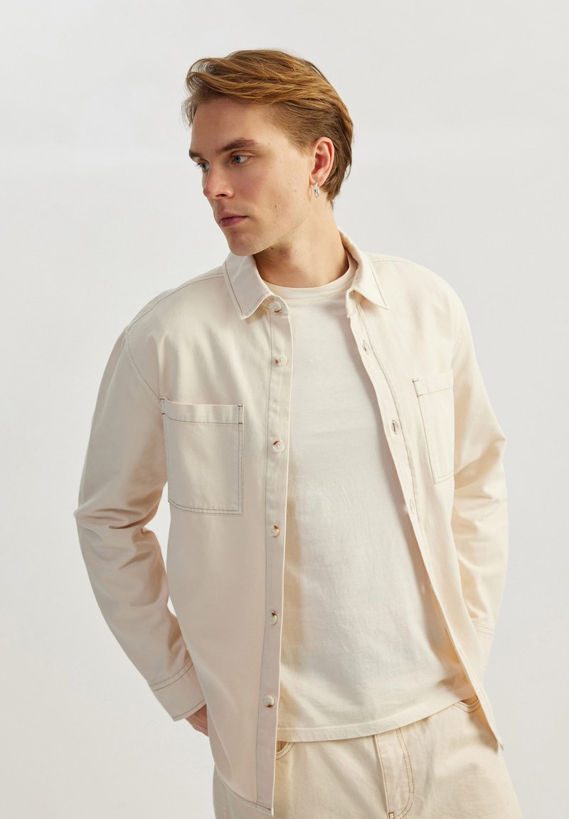 Lyscremet knap-up skjorte med lomme og afslappet pasform, lagd over en matchende crew neck t-shirt, alt i blødt stof.