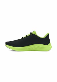 Baskets noires de sport avec un dessus texturé, des accents vert fluo sur la semelle et le col, et six lacets noirs passés à travers des œillets.
