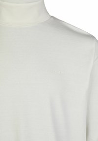 Weißer Rollkragensweater aus weichem Material. Mit schlanker Passform und einem dezenten Markenlogo in hellen Farben auf der Vorderseite. Glatte Textur.