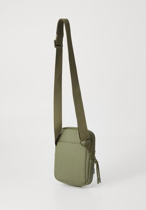 Olivovo zelená crossbody taška s textúrovanou látkou, obdĺžnikovým tvarom, nastaviteľným popruhom a zipsovým uzáverom s detailmi visiaceho hardvéru.