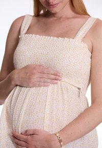 Gerafftes, weiches Kleid aus Stoff mit einem hellgelben Blumenmuster, quadratischem Ausschnitt und verstellbaren Trägern. Verfügt über einen seitlichen Reißverschluss für einen einfachen Zugang.