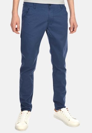 Mørkeblå bomulds chinos med en slim fit, frontlommer og bæltestropper. Matcher med hvide sneakers med en beige detalje på hælen.