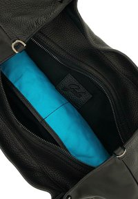 Interno di una borsa nera in pelle che mostra una foderatura blu brillante, una tasca con zip e un'etichetta del marchio in pelle nera con texture.