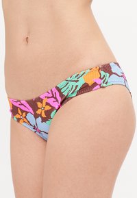 Barviti cvetlični bikini spodnji del z rebrasto teksturo, s pokrovi v rožnati, oranžni, zeleni in modri na rjavi podlagi.