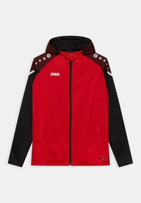 Rote Sportjacke mit Reißverschluss und schwarzen Ärmeln, strukturierten braunen Schulterakzenten und reflektierenden Details. Logo "JAKO" auf der Vorderseite.