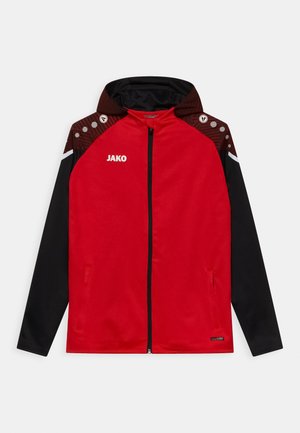 Veste de sport zippée rouge avec des manches noires, des accents d'épaule en brun texturé et des détails réfléchissants. Logo "JAKO" à l'avant.