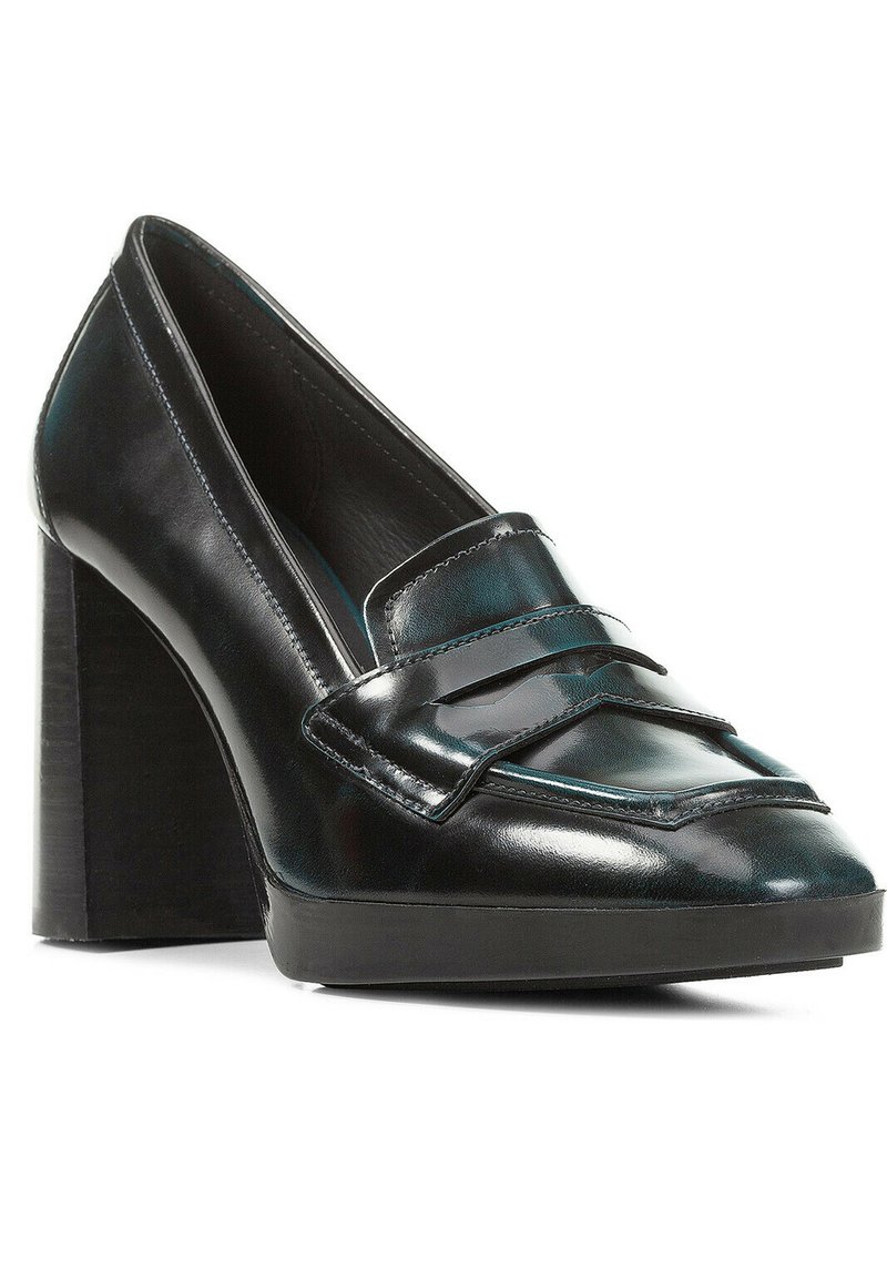 Mocasines negros de tacón alto con acabado de cuero brillante, que cuentan con un acento de correa elevada y un tacón cuadrado robusto. Textura suave.