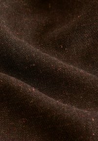 Tissu texturé marron foncé avec un tissage visible et des touches de couleurs plus claires, créant une apparence riche et stratifiée. Surface douce et lisse.