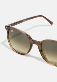 Ochelari de soare tortoise maro cu lentile gri degrade, cadru din plastic ușor și logo-ul Ray-Ban argintiu pe temple.