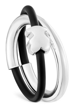 Deux anneaux entrelacés, un argenté et un noir avec un pendentif trèfle à quatre feuilles en argent attaché à l'anneau noir.