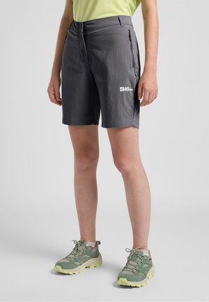 Grijze lichtgewicht shorts met een gestructureerd oppervlak, voorzien van een ritszak en het Jack Wolfskin-logo. Gecombineerd met groene wandelschoenen.