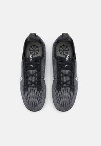 Ett par mörkgrå stickade löparskor med svarta snören, vita swoosh-logotyper på sidorna och spiraldesign på innersulorna, sedd ovanifrån.