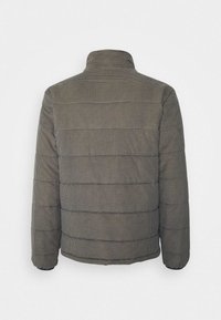 Puffjacka i ett rutigt mönster med hög krage, quiltad textur och elastiska ärmar. Primärt i mörka nyanser med ljusa accenter.