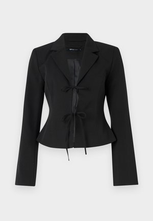 Črn skrajšan blazer s prilegajočo silhueto, dolgimi rokavi in satenskimi zaveznicami spredaj. Gladka tkanina s klasičnim ovratnikom.