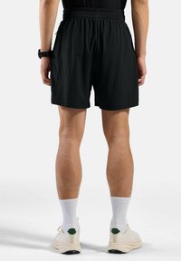 Zwarte shorts met een elastische tailleband, met een relaxte pasvorm. Draag ze met witte enkelsokken en lichtgekleurde sportschoenen.
