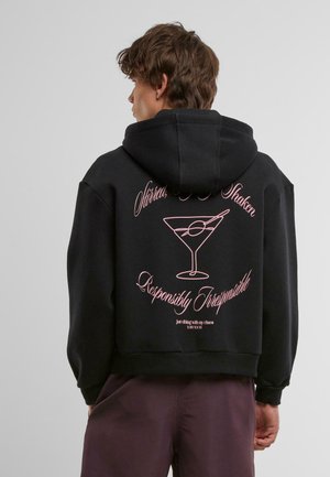 Svart hettegenser med rosa grafisk tekst og et martini-glassdesign på baksiden. Mykt stoff, avslappet passform, cropped stil.