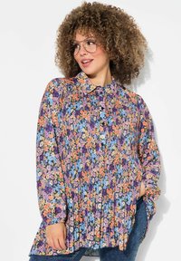 Květinová blůza vyrobená z lehkého materiálu s sklady. Obsahuje barevný vzor fialových, oranžových a modrých květin a límeček.