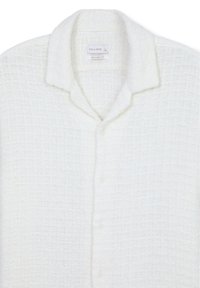 Camicia bianca con bottoni, caratterizzata da un tessuto testurizzato con un motivo a rete, un colletto e una vestibilità rilassata.