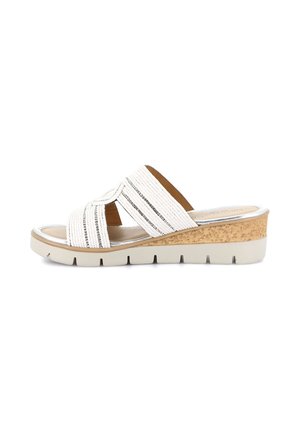 Sandalo con zeppa bianca con cinturini incrociati e testurizzati e suola con zeppa in sughero con suola bianca scanalata, mostrato di profilo laterale.