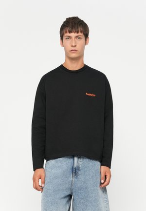 Black long-sleeve crewneck sweatshirt features an orange "Replay Inc." logo on the chest, made of cotton with a relaxed fit and raw hem.