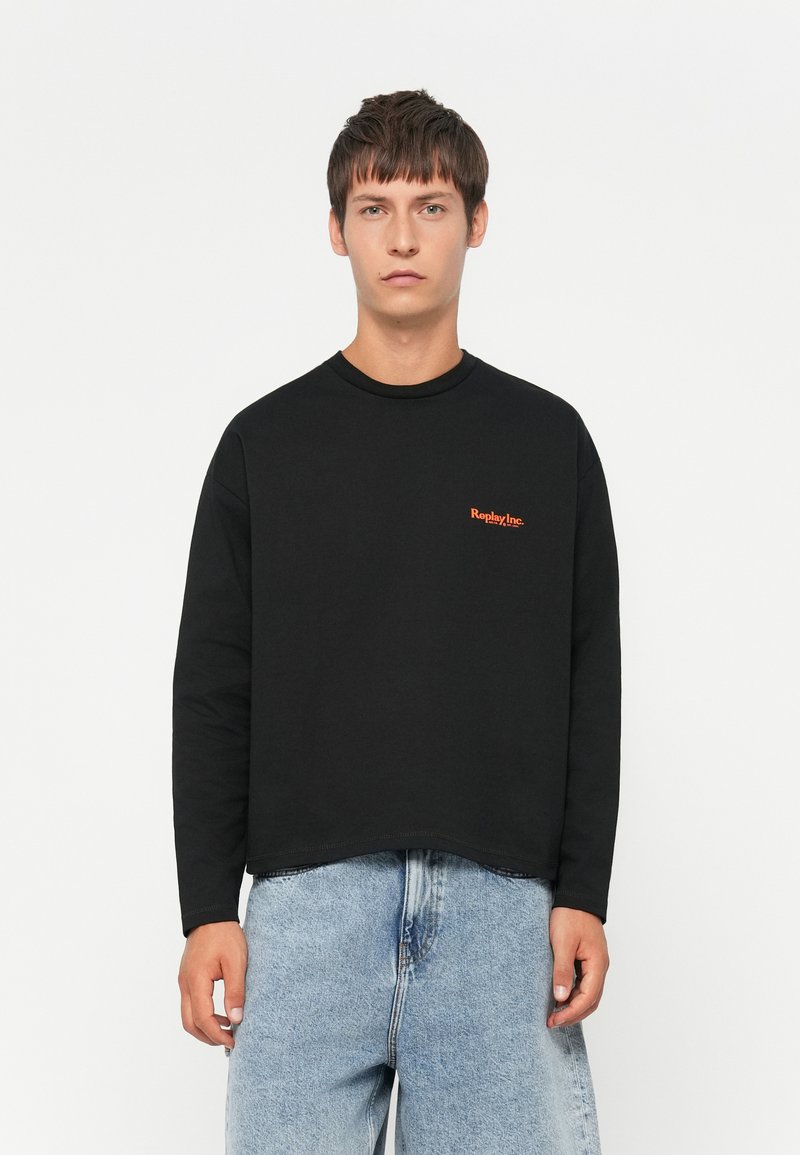 Black long-sleeve crewneck sweatshirt features an orange "Replay Inc." logo on the chest, made of cotton with a relaxed fit and raw hem.