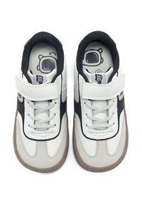 Weiße und marineblaue Sneakers mit einem oberen Teil aus glattem Leder, Schnürung und Klettverschluss, gepolstertem Kragen und Gummilaufsohle, mit Charakterdesigns im Inneren.