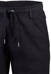 Czarne luźne spodnie z elastycznym pasem, zapięciem na guzik, szlufkami na pasek oraz przednimi kieszeniami, wykonane z miękkiego materiału.