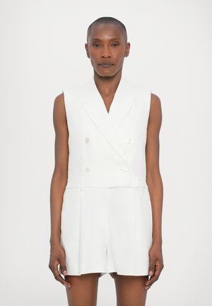 White linen double-breasted vest with a fitted waist and pleated shorts. Features a shawl collar and two front buttons for closure.